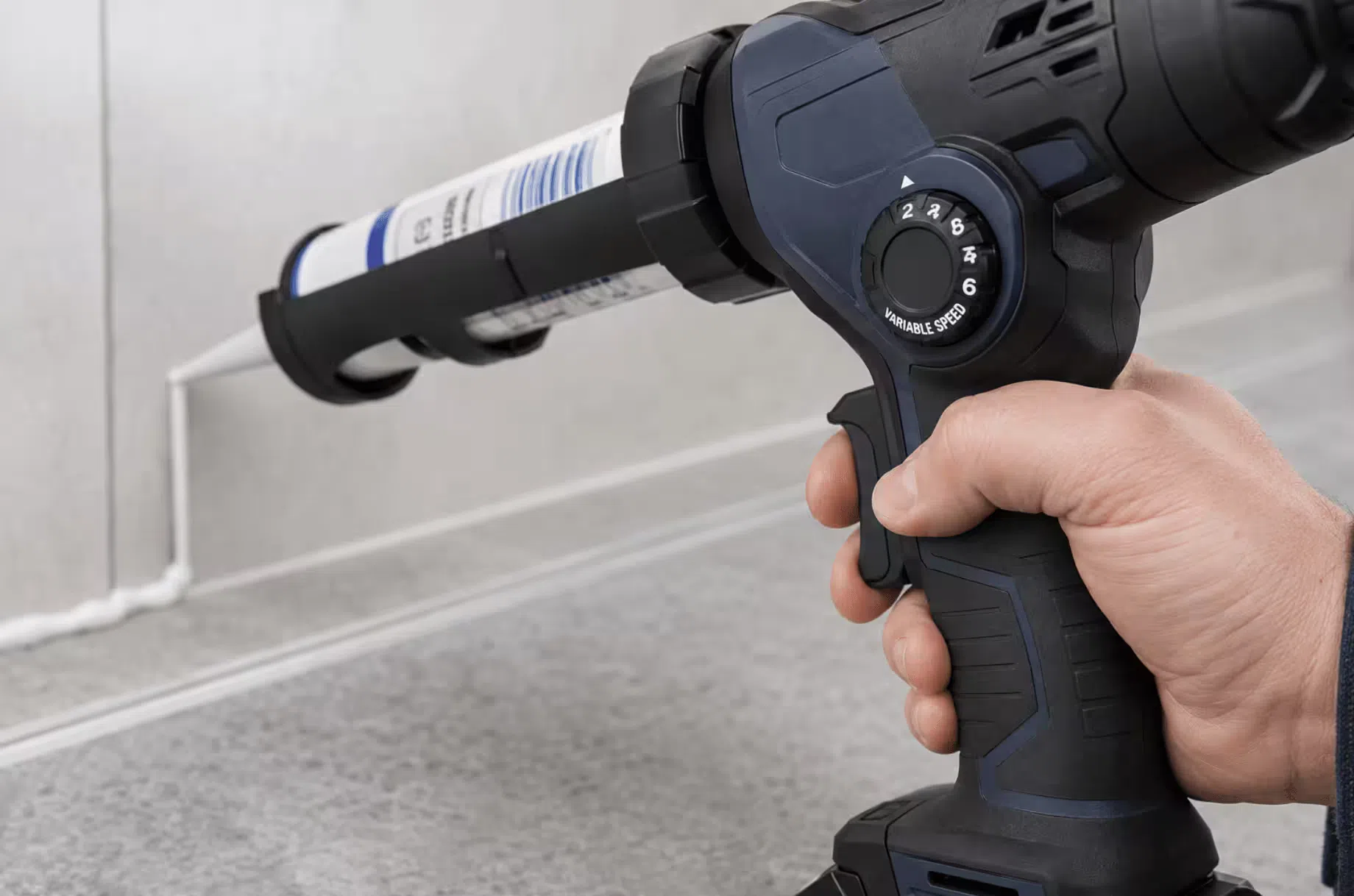 Variable speed dial and trigger on a cordless caulking gun showing 6-speed settings for flow rate control